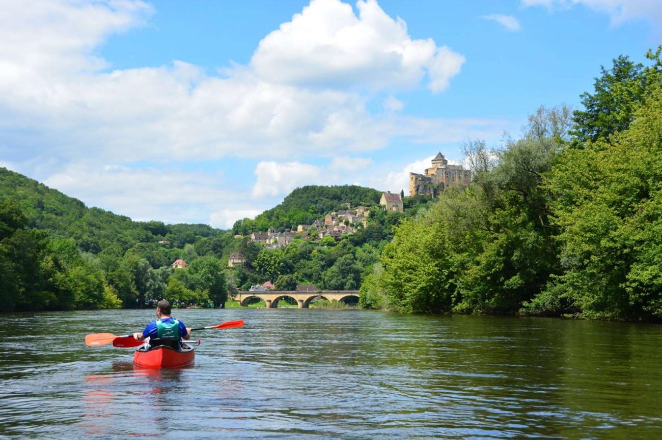 Des canoës rouges sur la Dordogne au pied d'un pont