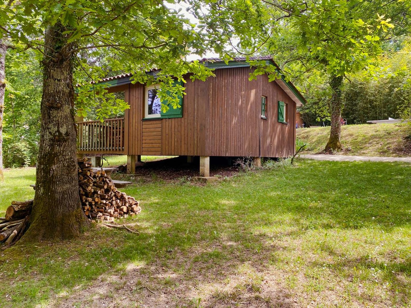 Un chalet en bois entre deux chênes
