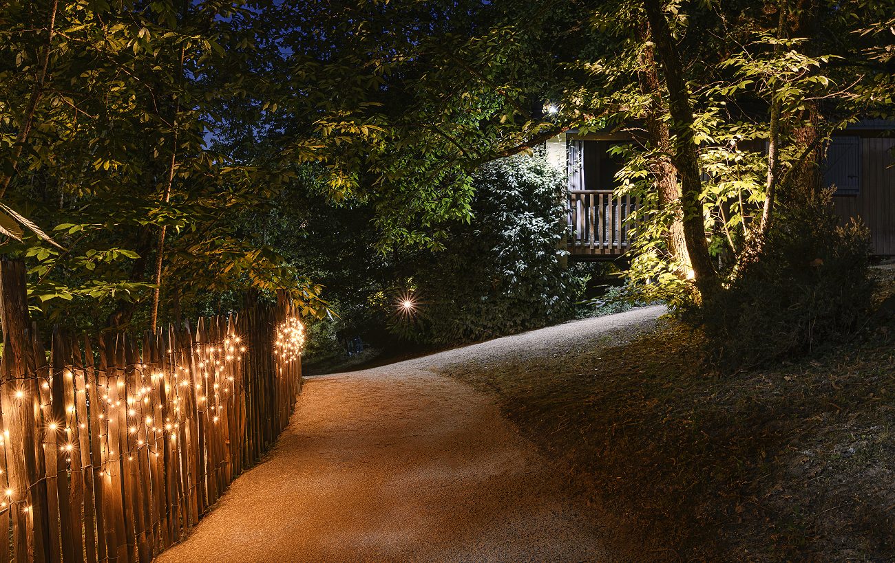 Une allée du domaine la nuit, bordée d'une guirlande lumineuse