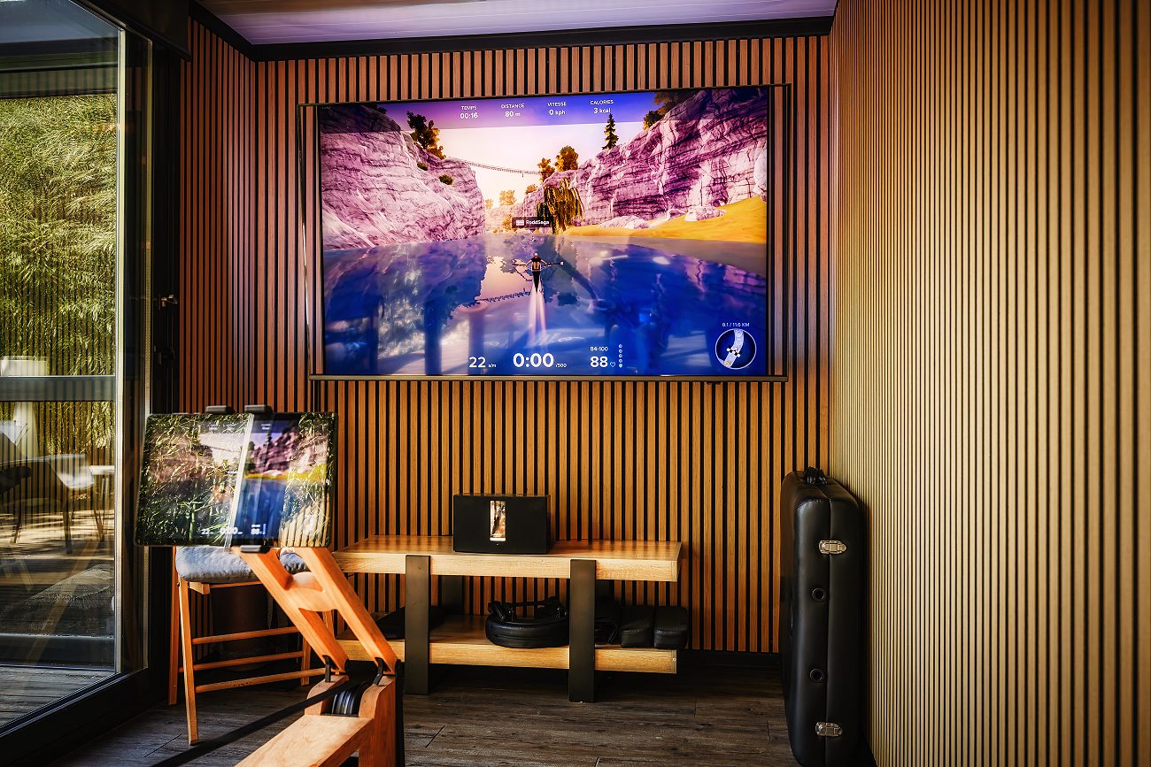 La salle de sport : le rameur en bois face au grand écran Zwift